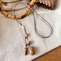 Vista macro dettagliata della collana artigianale con ciondolo a ghianda e corda cerata - Ghianda Grande Marrone