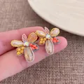 Close-up of crystal flower earrings with beaded petals and shimmering center stones - Yellow