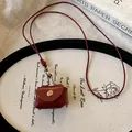 Detailed view of vintage reddish-brown leather mini pouch necklace on artistic tray - Necklace / Burgundy