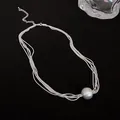 Close-up of a minimalist silver multi-layered necklace with a large round metal ball pendant - Silver