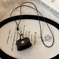 Vintage black leather mini pouch necklace for earphones and coins, displayed on a decorative tray - Necklace / Black