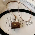 Close-up of brown leather mini pouch necklace on a decorative vintage tray - Necklace / Brown