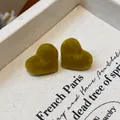 Detailed view of olive green flocked heart stud earrings on beige fabric background. - Heart / Small / Green