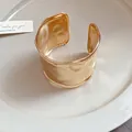 Detaillierte Nahaufnahme eines breiten goldenen Armreifs mit gehämmerter Textur-Stil - Gold