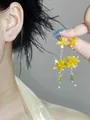 Forest style yellow flower tassel drop earrings with green zircon accents held by hand - Silver Earring Post Style / Yellow