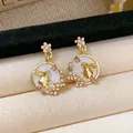 Elegant gold rabbit earrings with pink floral accents on a luxury cream jewelry display - Rabbit Flower Style / Gold