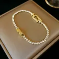Close-up of an elegant gold-toned bracelet featuring a horseshoe buckle and sparkling zircons - Gold