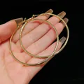 Detailed view of oversized gold-tone round hoop earrings showing size and metal finish - Oversized / Gold