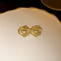 Detail shot of golden textured irregular bean stud earrings with a refined matte finish - Gold