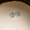 Close-up of silver-toned irregular textured geometric stud earrings on a ceramic plate - Silver