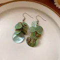 Vintage resin tassel earrings with iridescent green circular discs on white plate - Style 79 Ear Hook Disc Stacking (5942177792997) / Turquoise Green