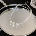 Close-up macro view of multi-strand silver necklace with three brushed metal beads on a mirror - Silver