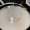 Close-up of elegant double-strand gold necklace with large white pearl pendant - Gold