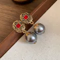 Detail view of vintage style earrings featuring red rhinestones and grey pearl dangles - Earrings / Gray