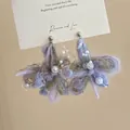 Macro view of handmade lavender yarn floral earrings with delicate white pearl accents. - Purple