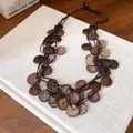 Detail view of irregular round coconut shell disks on a vintage ethnic tassel necklace - Necklace / Brown