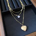 Detailaufnahme einer dreilagigen Goldhalskette mit Herzanhängern und Blumengravur. - Gold