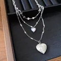 Detailansicht der silberfarbenen dreilagigen Herzkette mit graviertem Rosenmedaillon - Silber