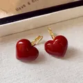Close-up detail of vintage red oil-dripped heart earrings on beige textured fabric - Heart Ear Buckle Style (HE23703) / Gold-Red