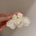 Dettaglio di orecchini eleganti con perle bianche e petali di fiori in rete color crema - Orecchini a Bottone con Perline e Fiori in Rete Albicocca Chiaro