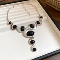 Gros plan d'un collier spirale géométrique vintage avec pierres noires et argent - Collier / Argent