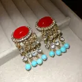 Dettaglio macro di orecchini vintage in oro con pietre rosse e perline turchesi - Oro con Rosso e Blu Multicolore
