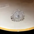 Vista macro di anello a sole in argento con strass scintillanti su un piatto bianco. - Stile Fiore Radiale Tondo (HR3001) / Argento