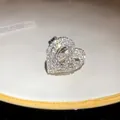 Dettaglio macro di un anello a cuore argento scintillante con pavé di strass - Stile Doppio Cuore Cavo (HR3002) / Argento