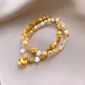 Primo piano dettagliato di bracciale in pietra di sole e agata con ciondolo a lucchetto - Stile 70 (Bicolore) / Oro/Giallo