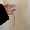 Close-up of silver-tone tassel earrings with cascading rhinestone chains and studs - Silver (Style 3 Silver Post)