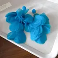 Dettaglio macro di orecchini a petali di tessuto blu vibrante su un vassoio grigio. - Ago d'argento / Blu