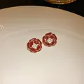 Close-up detail of elegant red camellia flower stud earrings with pearl center and gold trim. - Camellia Style (With Silver Earring Post)