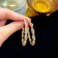 Elegant gold-tone hoop earrings with sparkling rhinestones in a geometric design - Rhinestone Twisted Hoop / Gold