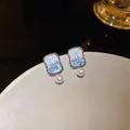 Macro detail showing blue crystal inlay and white pearl on silver square needle earrings - Square Style / Blue