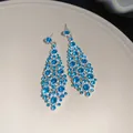 Primo piano di eleganti orecchini pendenti in strass blu con design a rombi irregolari. - Perno in argento - Argento - Blu