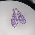 Primo piano di orecchini pendenti in zircone viola con forma a rombo irregolare. - Ago d'Argento-Argento-Viola