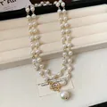 Dettaglio della collana di perle retrò francese con chiusura OT dorata e pendente. - Bianco