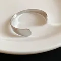 Macro view of a polished silver teardrop open cuff bracelet on a white porcelain plate - Plain Polished / Silver