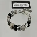 Close-up detail of a glass marble and silver beaded bracelet on a reflective surface. - Ink Flower Style (31#) / Silver & Black