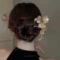 Détail d'une épingle à cheveux fleur dorée avec pompon dans un chignon chic - Or-Fleur