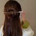 Vue détaillée d'une élégante épingle à cheveux chinoise avec pompon de fleur sur un chignon. - Pompon Fleur Blanche À Cinq Pétales Argent (60#)
