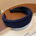 Close-up detail of a navy blue knitted fabric headband with a thick padded design - Blue