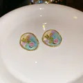 Close-up view of elegant pastel enamel earrings featuring a golden dragonfly and pink flower - Silver Needle / Gold-Blue-Purple
