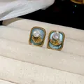 Detailed view of elegant teal enamel earrings with pearl and gold floral accents in vintage frames - Silver Needle / Gold-Blue
