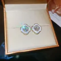 Detail of elegant flower stud earrings with white enamel and sparkling center stone. - Silver Needle / Gold-White