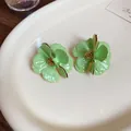 Elegant light green flower stud earrings featuring gold trim and silver needles on a white plate - Silver Needle / Green
