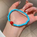 Handmade turquoise beaded bracelet with central red bead and gold accents - Blue & Red (94#)