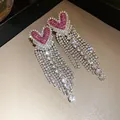 Dettaglio ravvicinato di orecchini a cuore con lunghe nappe di cristallo scintillante. - Perno in Acciaio - Rosa Rosso