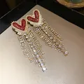 Dettaglio di eleganti orecchini a cuore rosso con lunghe nappe di strass scintillanti. - Perno per orecchini in argento - Rosso