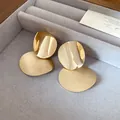 Detailed view of gold metal stud earrings featuring shiny and brushed finishes - Gold